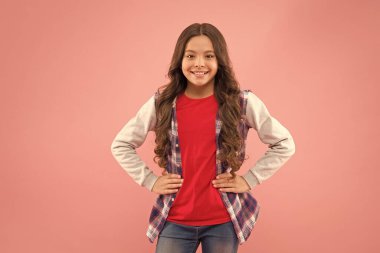 Genç olmak için güzel bir zaman. Çocuk modası. Gülümseyen okul kızı. Uzun saçlı çocuk. Mutlu çocuk. Mutlu çocuklar günü. Çocukluk konsepti. Küçük pembe arka plan. Şık ve şık. Mutlu bir hayat yaşamak