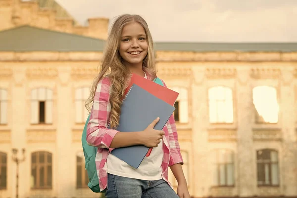 School club. Modern education. Private schooling. Teen with backpack. Stylish smiling schoolgirl. Girl little fashionable schoolgirl carry backpack school building background. Schoolgirl daily life