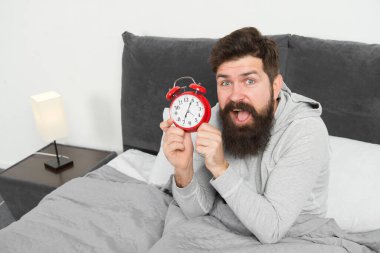 Sakallı hippi uykulu adam uyanıyor. Sağlıklı yaşam tarzı için günlük program. Sabah yine mutsuz. Çalar saat çalıyor. Sabah erken uyanma sorunu. Erken kalk. Erken kalkmak için bahşiş.