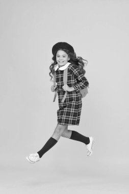 Şık genç üniversite öğrencisi atlaması. Sırt çantalı küçük kız okula gidiyor. Eğitim konsepti. Okul ve moda. Öğrenci üniformalı çocuk. Sarı arka planda Fransız bereli bir çocuk. Acele et.