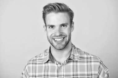 Tıraşsız mutlu genç adam gülümsüyor. Sağlıklı dişleri sarı arka planı var.