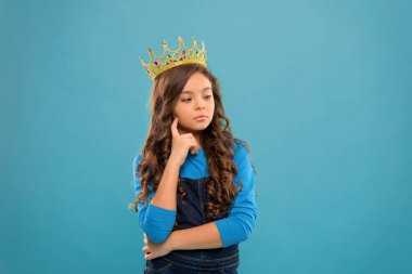 Düşünceli bebek. Küçük hanım prenses. Kız taç takıyor. Prenses terbiyesi. Güzellik yarışmasının galibi. Uluslararası güzellik yarışması. Çocuk prensesin altın taç sembolünü takıyor. Prenses ol.