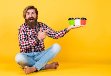 Mutlu, sakallı, sakalsız, şık saçlı, sıradan kıyafetler giyen, kahve içen, kahve mahsulü sunan yakışıklı adam.