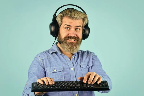 Play computer games. Online gaming platform. Gaming modern leisure. Cyber sport arena. Gaming PC build guide. Graphics settings. Gaming addiction. Man bearded hipster gamer headphones and keyboard
