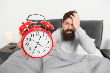 Erken kalktığın için bahşiş. Sakallı hippi adam çalar saatle yatakta uykulu yüz. Sabahın erken saatlerinde uyanma sorunu. Çalar saati getir. Yine uyuyakalmışsın. Erken kalkmak için bahşiş.