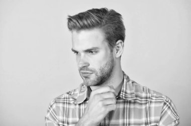 Tıraşsız yüzlü, şık saçlı, sarı arkaplan, ciltli yakışıklı beyaz bir adam.