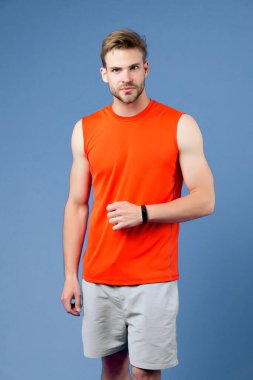 Menekşe duvarında spor akıllı adam. Turuncu yelekli ve mavi şortlu bir sporcu. Antrenman ve spor için moda aksesuarı. Sağlıklı yaşam tarzı için yeni teknoloji. Spor, spor ve sağlık.