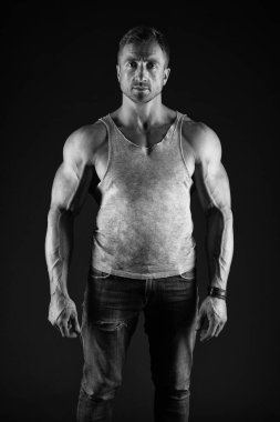 Hayata uygun. Formda adam siyah arkaplan. Güçlü adam kot pantolon ile fanila giyer. Kolları pazılı bir sporcu. Kas geliştirme. Spor ve spor. Sağlık ve diyet. Sağlık ve koruma