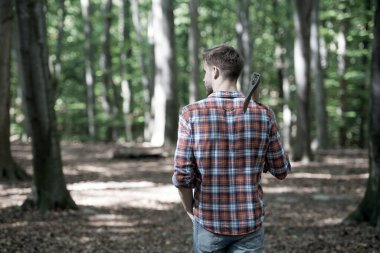 Ormanda balta ve doğa ile yürüyen ormancı.