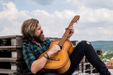 Tişörtlü, beyaz, vahşi hippi akustik gitar ve müzik çalıyor.