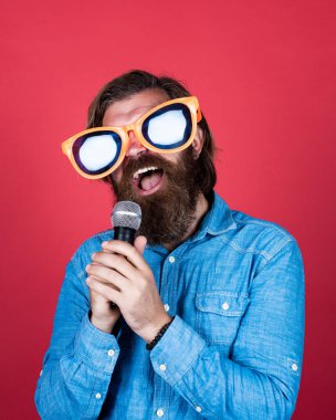 Mikrofonlu komik sakallı adam. Parti gözlüklü vahşi beyaz hippi. Karaoke şarkıcısı. Tıraşsız, uzun saçlı adam. Berber ve kuaför. Erkek mikrofonla şarkı söyler