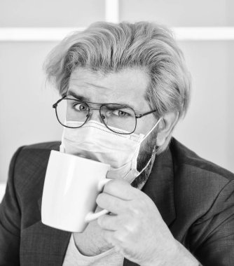 Sabah kahvesi. Bir fincan kahve içen adam. Kişisel temas olmadan. İnternette iş yapmak. Coronavirus karantinası. Online eğitim ve dersler. İş yerinde solunum riskleri yaygındır