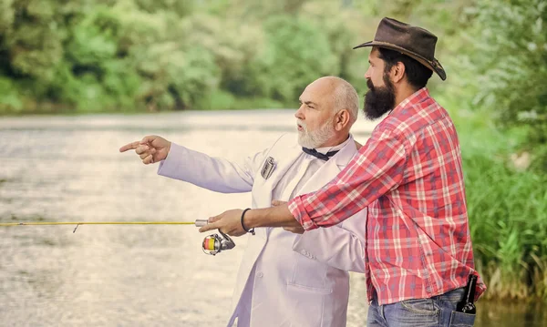 Learn to fish. Fish with companion who can offer help in emergency. Fishing skills. Men friends relaxing nature background. Personal instructor. Bearded man and elegant businessman fish together