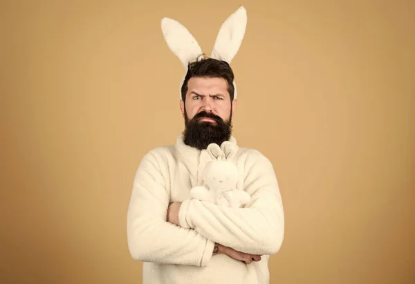 Guy bearded hipster weird bunny with long white ears beige background. Easter rabbit. Man wearing rabbit suit. Funny bunny man soft ears. Easter activities concept. Weirdo concept. Celebrate Easter