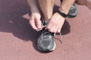 Ayakkabı bağcıklarını bağlayan eller, arka plan çalışması. Spor ayakkabı bağcığını spor ayakkabısına bağlayan bir sporcunun elleri. Koşu ekipmanı konsepti. Erkek eli ile bağlayan ayakkabı bağcıkları