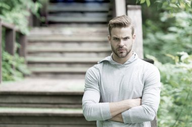 Kaslı ve kendinden emin. Yaz günü kaslı bir adam. Parkın merdivenlerinde kaslı kollarını çapraz tutan atletik adam. Yakışıklı sporcu ya da sporcu kas gücü ve gücü gösteriyor.