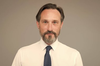 Gri sakal onun için önemli. Yaş ve tecrübe. Yakışıklı, kendine güvenen bir manken şık beyaz bir gömlek giyer. Özgüven duygusu. Erkek modası. Moda dükkanı. Sakallı, olgun bir yüz.