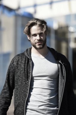 Gri tişörtlü adam güneşli bir günde yürüyor.