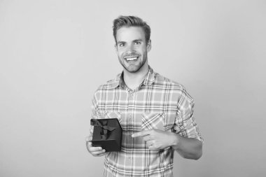 Arkadaş canlısı erkek tezgahtar. Tatil hediyesi. Kıvırcık saçlı modacı şaşırdı. Kara Cuma ve siber pazartesi. Yakışıklı genç adam hediye kutusunu tutuyor. Neşeli adam alışverişe gidiyor. işaret parmağı