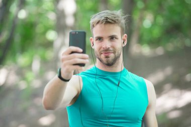 Telefondaki spor uygulaması. Dijital spor. Akıllı saat. Spor giyim sektöründeki atletik adam selfie çekiyor. Açık hava antrenmanı. Fitness uygulaması. Ui ux kavramı. Modern sporda bir alet. İz sürücüdeki kaslı adam. bağlantı araması
