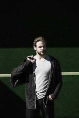 Yeşil arka planda spor çantalı bir adam.