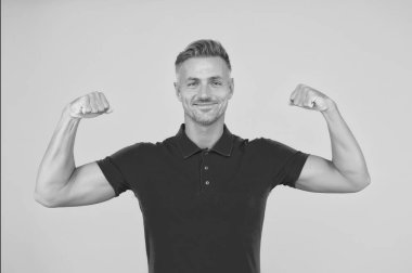 Güçlü atletik adam kırmızı tişörtle gülümsüyor kaslı kollar sarı arka plan, güç