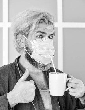 Virüsten korumak için maskeler. Viral enfeksiyondan korunmak için maske takıyor. Adam tıbbi maskeli kahve içiyor. Sabah evde, koronavirüsle kendini izole ediyor. Pandemik karantina. Anti-virüs maskesi