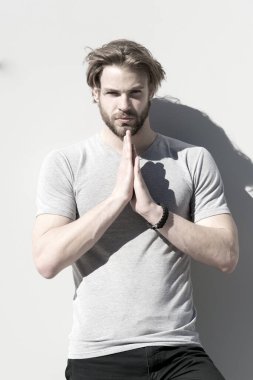 Güneşli bir günde dua eden elleri tişörtlü adam.