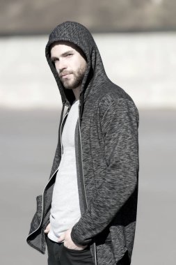Kapüşonlu sakallı maço açık havada, moda. Adam eşofman üstü giyer, gündelik tarzda. Erkek modası, tarz, spor giyim. Aktif ve sağlıklı insanlar için yaşam tarzı, spor