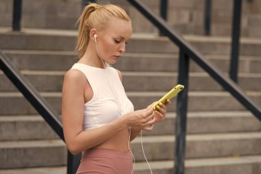 Akıllı telefon spor takip uygulaması kullanıyor. Seksi kadın ekrandaki akıllı telefona dokunuyor. Sağlık ve zindelik için akıllı bir cihaz. Akıllı egzersiz. Yeni teknoloji ve spor. Eğitimle ilgili akıllı olmak