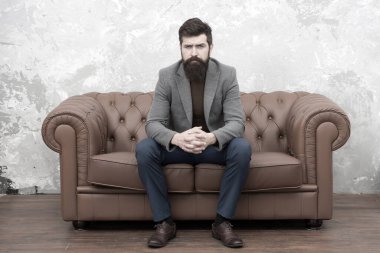 Şık ama sıradan. Sakallı adam kanepede dinleniyor. Gayri resmi takım giyen adam ya da iş adamı. Uzun sakallı ve modaya uygun saç stili olan moda adamı. Hipster yaşam tarzını takip eden zalim bir adam.