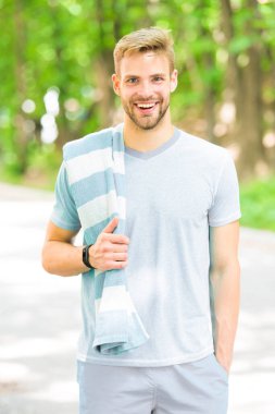 Sporcu sağlıklı bir yaşam tarzını destekliyor. Yaz günü sporcu ya da antrenörünüz kutlu olsun. Açık havada antrenman yaparken havlu kullanan formda bir sporcu. Yakışıklı sporcu ya da spor koçu doğal manzarada gülümsüyor.