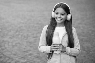 Gençler için sağlıklı bir içki. Formdan sonra susadım. Kız bakım vücut sıvısı. Aktif ve sağlıklı çocuklar su içer. Kulaklığında meyve suyu şişesi olan bir çocuk. Okula dönüyorum. çocuklukta sağlık hizmetleri