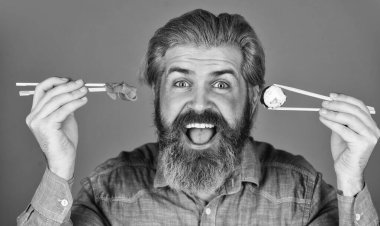 Suşi siparişi. Sushi teslimatı. Mutlu adam suşi yer. Çubuklu suşi ve zencefil. Japon mutfağı. Japonya 'da geleneksel yiyecekler. Şef yemek servisi. Asya yemeği