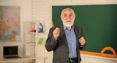 İyi öğretmek için ilham verici. Coğrafya haritasının yanındaki gözlüklü hoca. Okula dönüyorum. Sınıfta ders. Geometriyi kolayca öğren. Matematikte iyi ol. Tahtada kıdemli öğretmen.