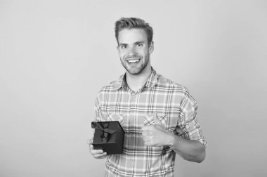 Siber pazartesiden sonra alışveriş yaptıktan sonra kareli tişörtlü gülen adam hediye kutusu alışverişini işaret ediyor.