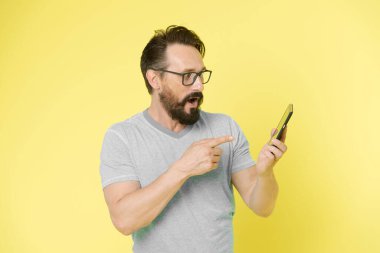 Gözlüklü adam akıllı telefonu işaret ediyor. Akıllı telefon için adam mutlu kullanıcı etkileşimli uygulama. İnsanlar online iletişimden faydalanıyor. Adamın sakallı etkileşimli mobil arayüz uygulaması