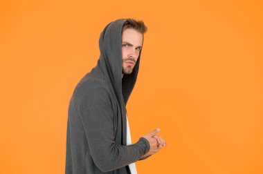 Döneceğim. Günlük yaşam için rahat kıyafetler. Moda adamı sarı arka plan. Moda bakışı. Yakışıklı adam kapüşonlu şık bir manto giyiyor. Sıradan erkek giyimi. Moda trendleri. Gençler için modern kıyafetler
