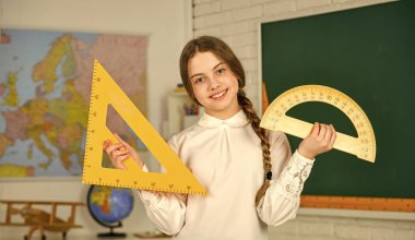 Matematik dersi için elinde cetvel tutan küçük bir çocuk. Matematik önemlidir. Matematik için geometrik aletleri olan şirin bir kız öğrenci. Bilim ve Teknoloji. İlkokul matematiği ya da matematiği