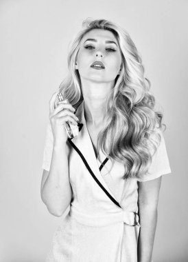 Her şey güçle ilgili. Saç yağı spreyi. Güzellik ve moda. Dükkan asistanı doğal kozmetik ürünleri sunuyor. taze ve eşsiz bir koku. Elinde seksi kadın parfümü var. kıvırcık saçlı güzel sarışın kız.