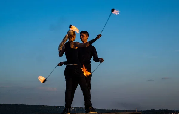 sexy couple of dancers perform fire performance with burning poi blue sky outdoors, hot