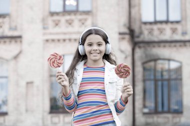 Güzel bir an. Mutlu çocuklar günü. Sağlıklı bir yaşam tarzı. Lolipopu olan liseli kız. Kulaklıklı mutlu çocuk. Öğrenci müzik dinler ve şarkı söyler. Okula dönüyorum. Açık havada mutlu bir güzellik. çocuk eğitim yenilikleri