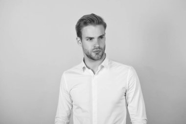 Beyaz tişörtlü yakışıklı adam turuncu arka planda duruyor, iş modasında.