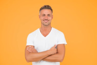 Kendinden emin ve iyimser. Kolları çapraz sarı olan kendine güvenen bir adam. Mutlu adam özgüvenle gülümser. Moda modelinin kendine güveni tam. Sıradan bir tarz. Erkek gardırobu. Kendinden emin ve mutlu.