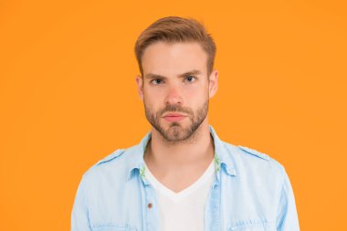 Tıraşsız, tüylü yakışıklı bir adam. Erkek yaz modası. Ciddi adamın sarı arka planda saçları var. İnsani duygular. Havalı saç stili olan seksi çocuk gömlek giyiyor.