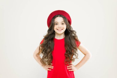 Kişisel tarzını takip ediyor. Fransız tarzı şapkalı küçük kız. Uzun kıvırcık saçlı, bereli mutlu kız. Sarı arka planda Parisli bir çocuk. Yaz modası ve güzellik. çocukluk. Kuaför salonu.