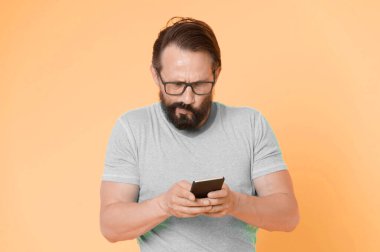 Gözlüklü adam kafası karışmış, akıllı telefon kullanıyor. İnsan kullanıcısı uygulama akıllı telefonuyla etkileşim kurar. Sakallı, olgun etkileşimli mobil arayüz uygulaması. Olgun insanlar için dijital cihazlara alışmak zor.