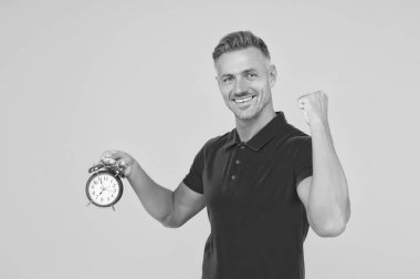 Mutlu beyaz adam güçlü bir kol tutuyor alarm saati sarı arka plan, dakiklik