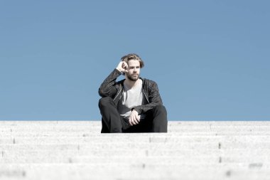 Maço güneşli mavi gökyüzünde merdivenlerde oturur, perspektif