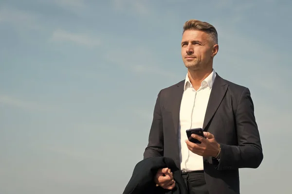 Mobile communication. Successful and motivated business man. Businessman well groomed hairstyle. Make decisions on the go. Business concept. Business life. Man classic style blue sky background.